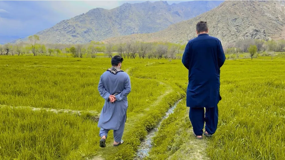 Travelers looking toward a green valley and mountains in Afghanistan